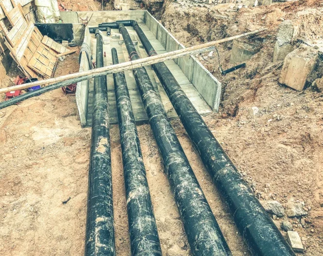 black polypropylene long pipes are laid underground for communications construction of a new microdistrict with houses and sewerage photo